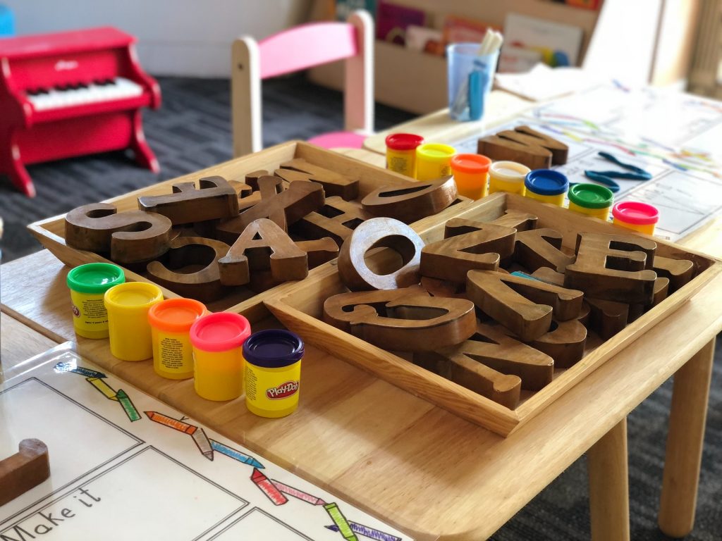 PRESCHOOL CLASSROOM WITH LETTER BLOCKS AND PLAYDOUGH ON DESK