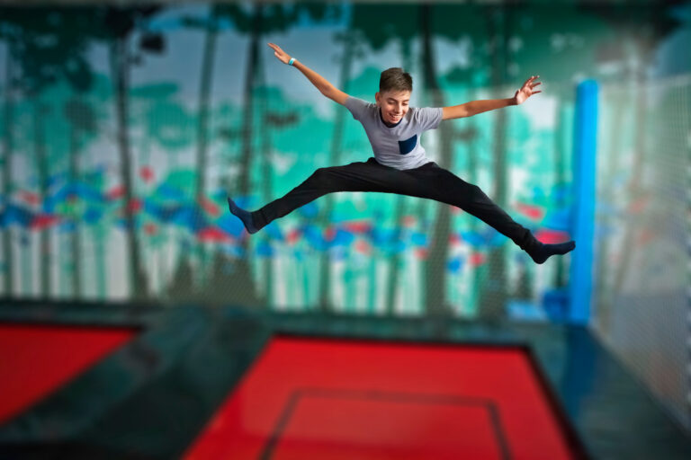 cheerful teen boy jumping on trampoline