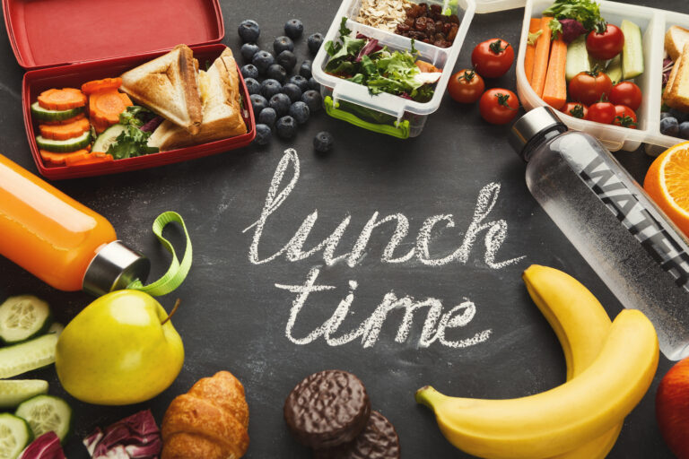 Lunch boxes filled with healthy food on black board